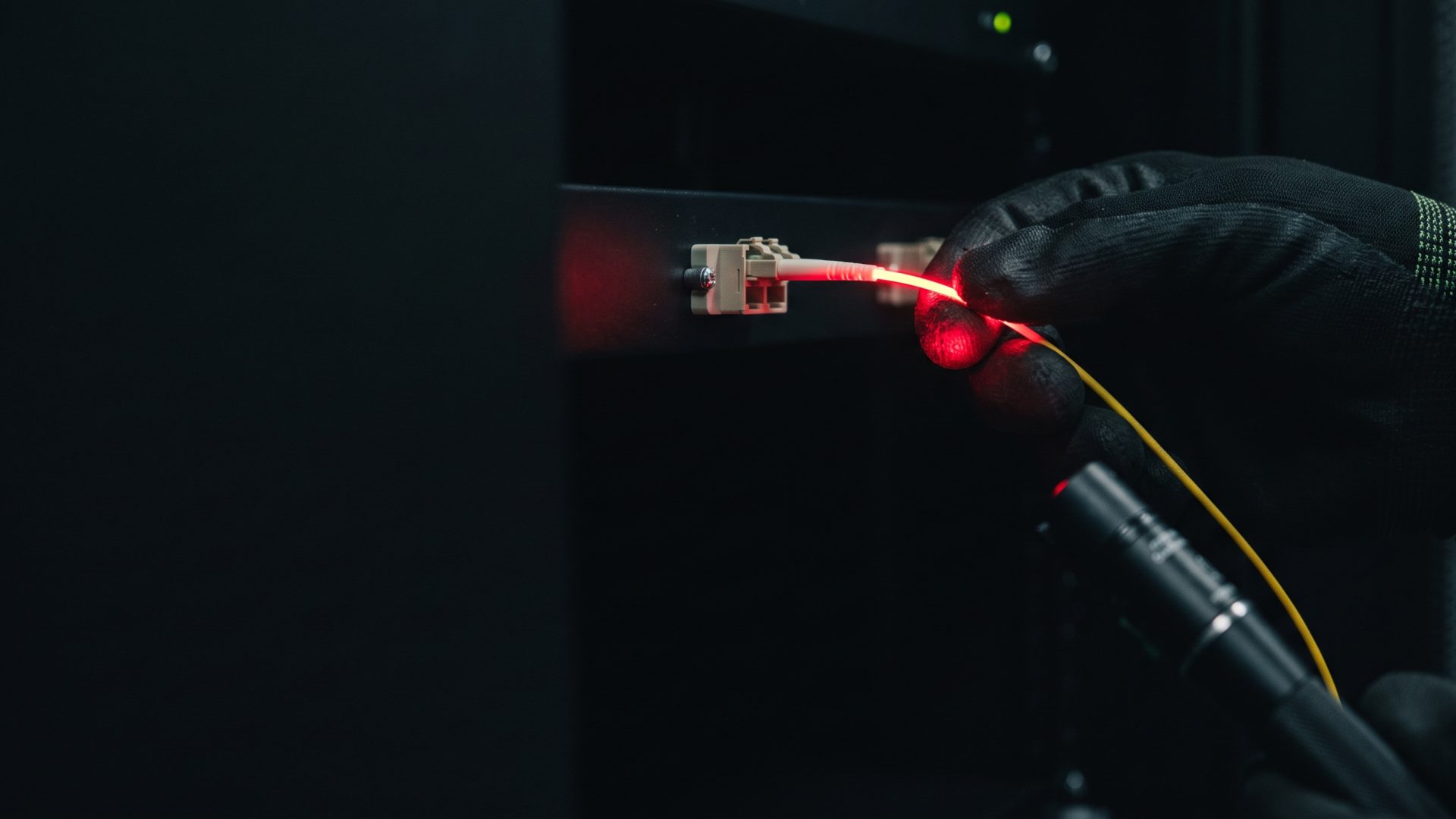 Techniker lokalisiert eine Glasfaserstörung mit rotem Visual Fault Locator am Patchfeld